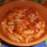 Pasta fresca fatta in casa condita con pomodoro e mozzarella filante al forno